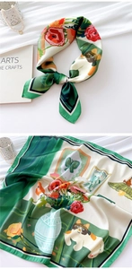 Detailed macro view showing the floral and cat print texture of the green silk scarf