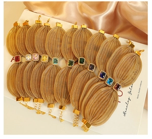 Detailed row of wide vintage gold mesh bracelets with multi-colored gemstone inlays
