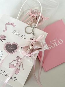 Pink satin ballet girl bow pendant with pearls next to a ballet theme gift bag