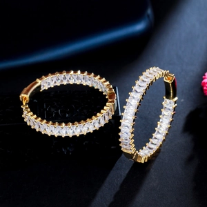 Detail of gold C-shaped hoop earrings with rectangular baguette-cut cubic zirconia