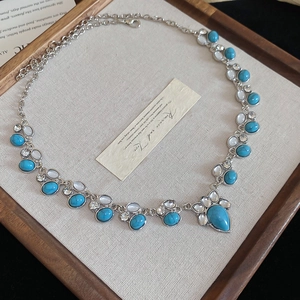 Close-up of ethnic turquoise and white gemstone pendant with silver vintage chain