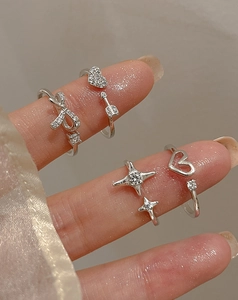 Detail of four silver rings with heart, bow, and star charms with micro-pave crystals