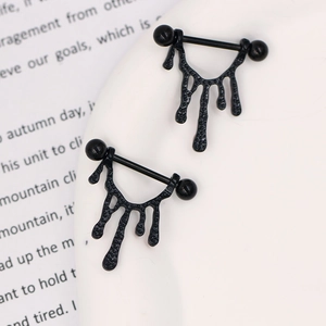 Detail showing black metal nipple rings with a unique melting drip design on white plate