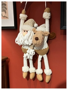 Detail of plush Santa and reindeer long-legged hanging decorations on a red wall