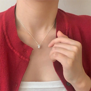 Minimalist 925 sterling silver pearl necklace with bow pendant on a model's neck