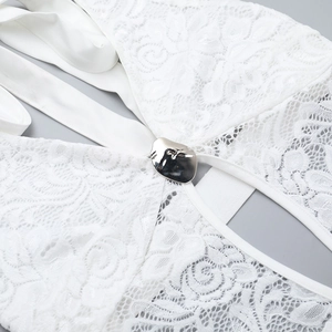 Vue détaillée de la dentelle florale blanche et de la boucle métallique sur la combinaison