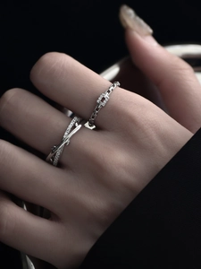 Detailed close-up of a silver crisscross ring and geometric band with shimmering diamonds