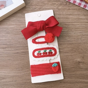 Detail of 4-piece red hair clip set featuring fabric bow and cherry embroidery for girls