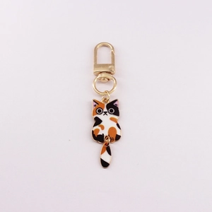 Detail view of calico cat enamel keychain with movable tail and golden D-ring clasp