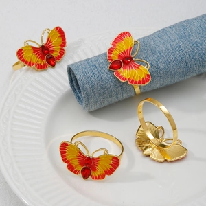 Golden dragonfly napkin rings with colorful enamel and red gems on a white ceramic plate