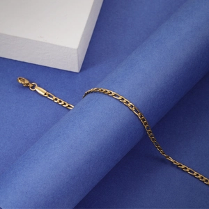 Detailed close-up of gold plated stainless steel Figaro chain with a lobster clasp closure
