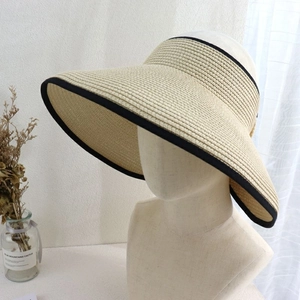 Detail of beige straw sun visor with black trim and elastic band on a display mannequin