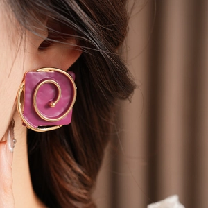 Close-up of vintage purple square earrings with golden spiral on a female ear