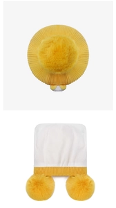 Detail of warm yellow knitted winter hats with soft pom poms and earflaps for children