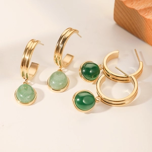 Macro view of C-shaped gold earrings with light and dark green jade pendants