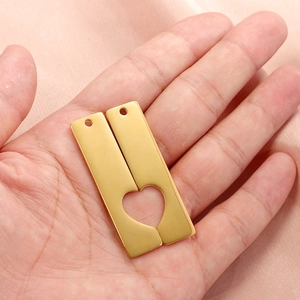 Polished stainless steel heart puzzle pendant keychain held over soft pink fabric