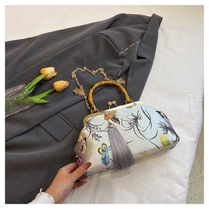 Detailed view of embroidery bag with bamboo handle, gold clasp, and grey tassel