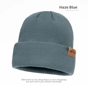 Close-up of knit texture and brown leather brand patch on foggy blue beanie hat