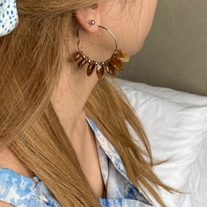Detail shot of silver hoop earrings with amber resin beads worn by a model