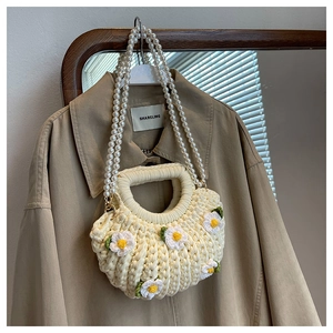 Detail of cream woven shell bag with daisy appliques and elegant pearl straps