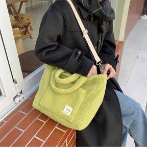 Detailed view of light green faux shearling tote bag with textured plush surface and beige strap