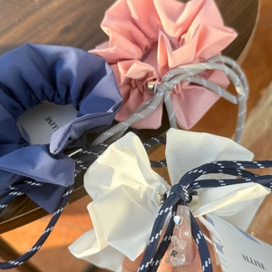 Detail of adjustable drawstring scrunchies in navy, pink, and cream with metal toggles