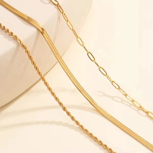 Detail of three layered gold chains featuring herringbone, rope and paperclip textures