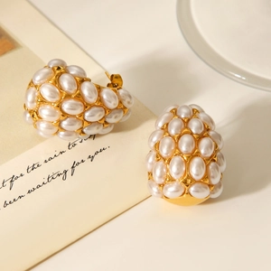 Macro detail of gold teardrop earrings featuring a cluster of elegant cream pearls