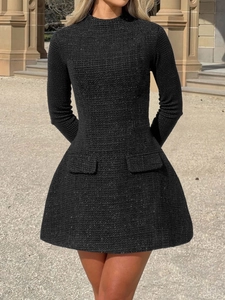 Detail of elegant black tweed mini dress with long sleeves and front flap pockets