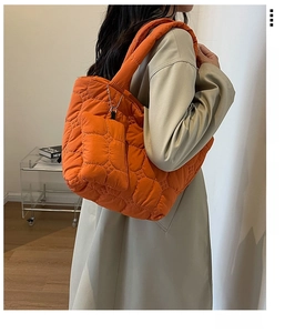 Detail of orange quilted puffer tote bag with matching mini coin purse charm on model