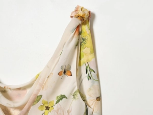 Détail de l'épaule d'une robe en mousseline fleurie avec nœud et imprimé papillon