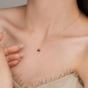 Elegant gold necklace with red rectangular ruby pendant and tiny diamond on female model