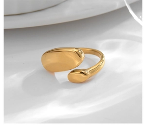 Macro shot of gold oval and teardrop minimalist open ring on white textured surface