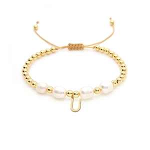 Macro detail of Baroque pearl and 18K gold-plated beaded bracelet with letter U charm