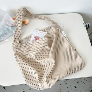 Detail of beige canvas tote with black heart patterns and MISS woven side label