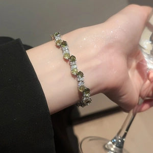Macro shot of silver bangle with sparkling green zircon and white crystals on wrist