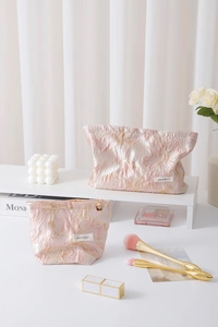 Detail of pink floral jacquard makeup bags with gold texture and logo label