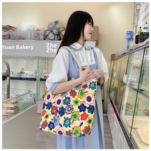 Floral canvas tote bag with white rope handles shown in a bakery shop setting