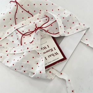 Detail of white canvas tote bag with red heart pattern and red drawstring closure