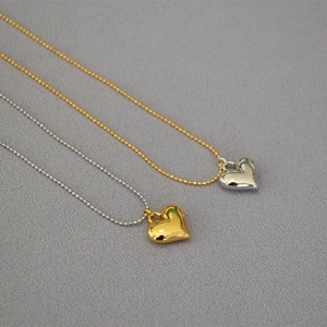 Detail of 3D heart pendants in gold and silver finish on delicate beaded chains
