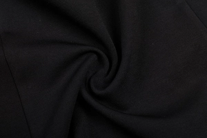 Detail of black knit fabric showing fine texture and draped folds of the cutout dress