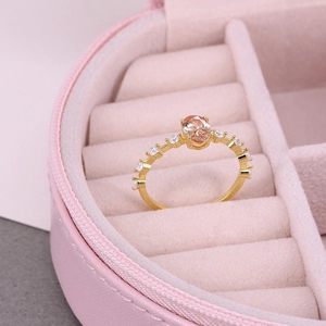 Close-up of golden ring featuring an orange oval stone on a pink jewelry box display