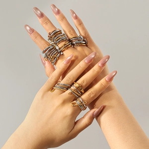 Stacked stainless steel rings in gold, silver and rose gold finishes on model's hand