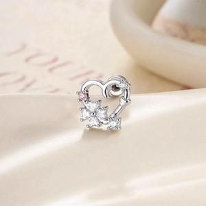 Silver hollow heart stud earring with micro-set floral stones on beige fabric