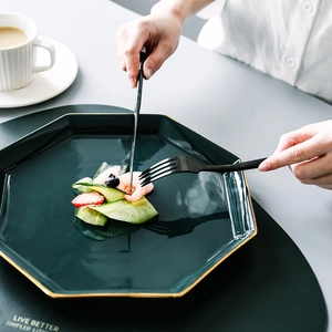 Elegantes Besteckset aus Edelstahl in Schwarz neben einem grünen Keramikteller