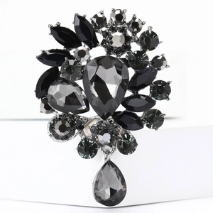 Macro shot of vintage style alloy brooch with black faceted gems and teardrop pendant