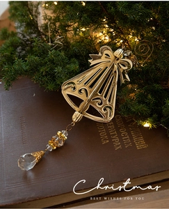 Close-up of golden Christmas bell with crystal pendant on a festive pine branch