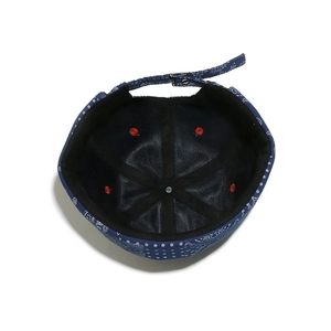 Detail of navy paisley docker hat featuring red eyelets and adjustable metal buckle