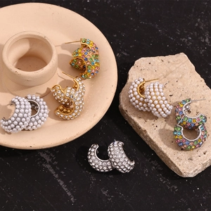 Detailed display of C-shape earrings with colorful rhinestones and pearls on stone