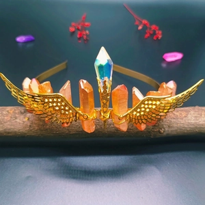 Detail of golden crystal crown featuring orange columns and hollow wing accents on wood
